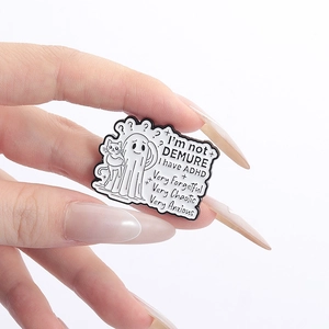 Close-up of white enamel ghost pin with cat and I'm not DEMURE text engraving