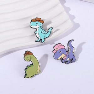 Detailansicht eines Sets aus drei bunten Cartoon-Dinosaurier-Emaille-Pins auf weißem Grund