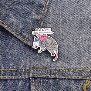 Cartoon opossum fairy godpossum enamel pin on denim jacket with funny quote bubble