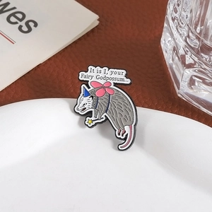 Macro shot of an enamel opossum fairy brooch with pink wings on a white plate