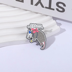 Detailed close-up of a cartoon opossum enamel pin with fairy wings on a display stand