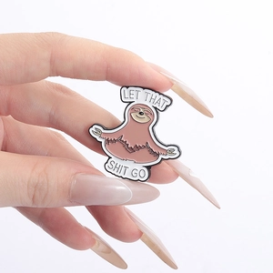 Detail shot of sloth enamel pin showing 'LET THAT SHIT GO' text and colorful metal finish