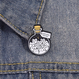 Pin's en émail Happiness Potion avec chats blancs dans un flacon sur veste en jean