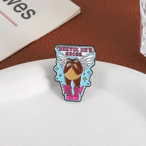 Detail of cartoon frog enamel pin featuring brown frog with wings and trendy pink boots