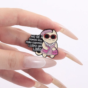 Detail of cartoon cat enamel pin with red sunglasses and book held by hand