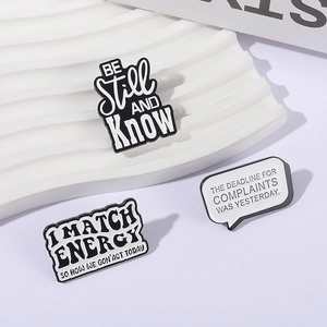 Detailed view of black and white enamel pins with motivational and humorous quotes