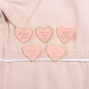 Gros plan d'épinglettes en émail rose en forme de cœur avec bords dorés sur tissu en denim