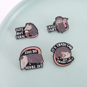 Detailed macro view of four funny enamel possum pins with humorous quotes on a blue tray