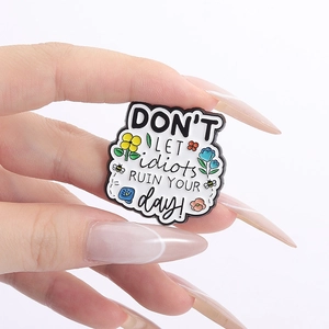 Détail macro d'une broche en émail avec fleurs arc-en-ciel et citation motivante