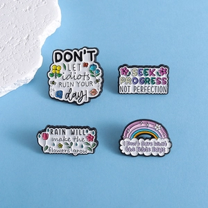 Détail de pin's en émail colorés avec citations motivantes et motifs floraux variés