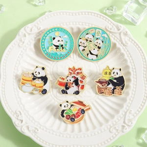 Close-up of enamel panda pins featuring mahjong and tea culture on white ceramic plate