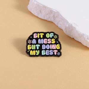 Inspirational enamel brooch with colorful lettering on a warm neutral background