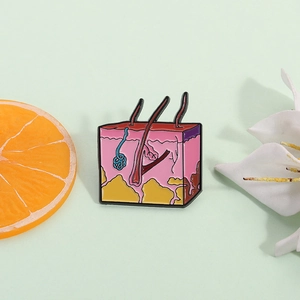 Creative skin anatomy enamel pin showing epidermis and dermis layers on a green surface