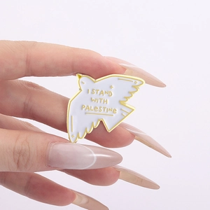 White enamel dove brooch with gold plating featuring I Stand With Palestine text