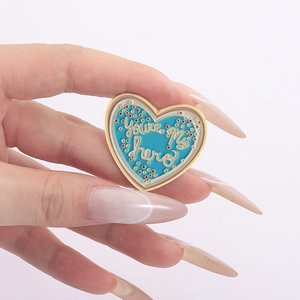 Blue heart enamel brooch with gold trim and You're My Hero lettering for clothes