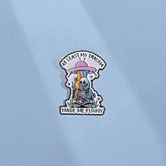 Detail of creative enamel pin with UFO skeleton design and funny trauma quote