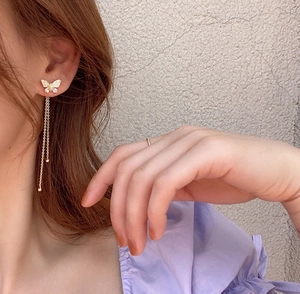 Detailed view of gold butterfly tassel earrings with sparkling zircon stones on a model