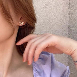 Close-up of golden butterfly earring with cubic zirconia studs worn by a model