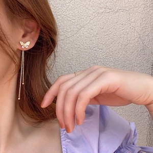 Golden butterfly tassel earrings with cubic zirconia inlay worn by a model