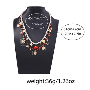 Double-layered pearl necklace with golden flower and clover charms on black bust display