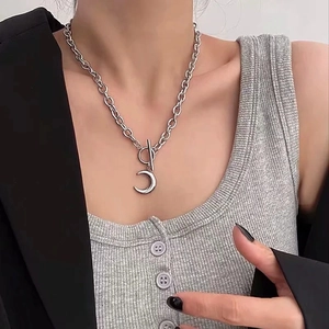 Dettaglio della collana argentata con pendente a luna e chiusura OT su un blazer nero