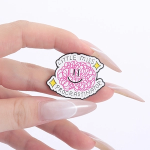 Detailed close-up of Little Miss Procrastinator enamel pin with pink scribbles and smiley