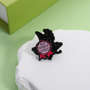 Detail of raven enamel brooch with Put Myself First lettering on a textured white stone