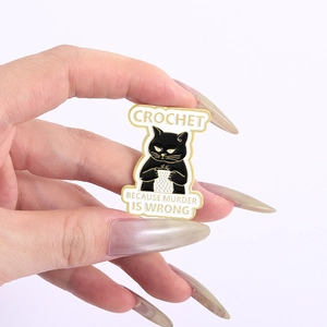 Detail showing hand-held black cat enamel pin with Crochet because murder is wrong text