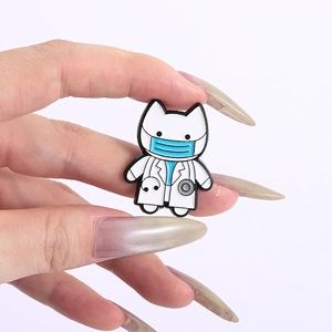 Close-up of a cartoon cat doctor enamel pin with stethoscope held by hand