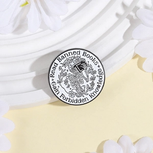 Detailed close-up of a skull reading books on a gothic circular enamel lapel pin