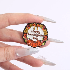 Detailed view of enamel Thanksgiving wreath pin with pumpkin and autumn motifs