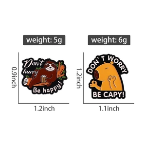 Detail of sloth and capybara enamel pins with Don't Hurry Be Happy text and black metal edge