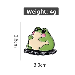 Detail view of a green frog enamel pin with Rootin' But Mostly Tootin' slogan, 4g weight