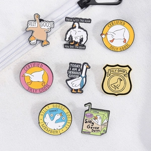 Detailed set of eight enamel goose pins with funny meme designs on white fabric background