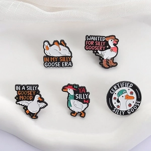 Detailed view of 5-piece funny cartoon white goose enamel pins on white fabric surface