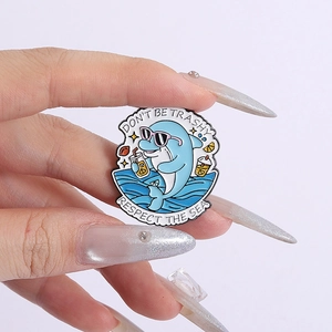 Detailed close-up of enamel dolphin pin with Don't Be Trashy and Respect The Sea slogans