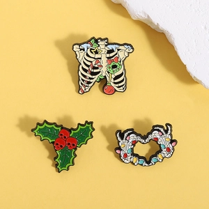 Macro view of dark gothic Christmas enamel pins featuring bone ribs and skull holly designs