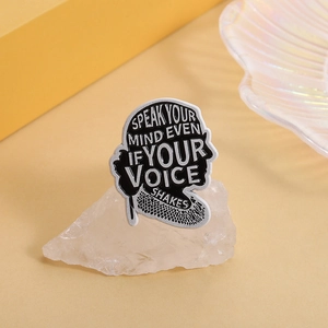Detailed shot of an enamel badge on crystal showing Speak your mind even if your voice shakes