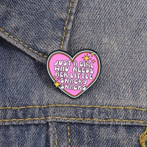 Spilla a cuore in smalto rosa con scritta fissata su tessuto denim blu