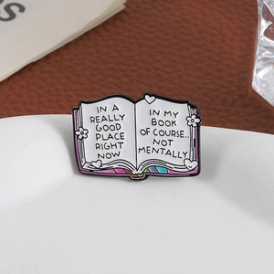 Creative book enamel pin with humorous English quotes on a white decorative display tray