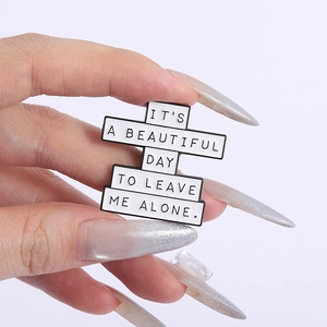 Gros plan sur le pin's en émail noir et blanc avec le message Leave me alone