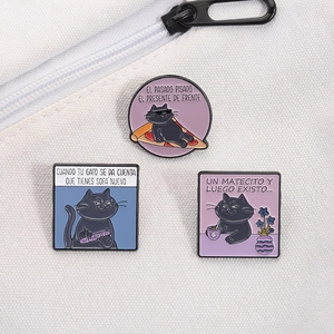 Detailed view of three cartoon black cat enamel pins on a white canvas bag