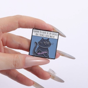Detail of square enamel pin showing a funny black cat illustration on blue background