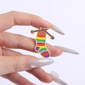 Rainbow knitted sock enamel pin with purple knitting needles and golden plating detail