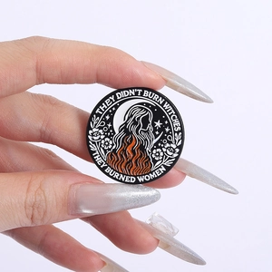 Detail of circular enamel pin with text 'They didn't burn witches they burned women'