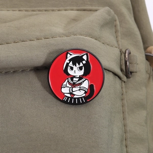 Détail d'un pin's émaillé de fille chat anime sur la sangle d'un sac à dos vert