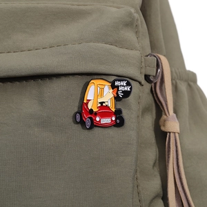 Detail of funny enamel duck driving a car pin on green canvas backpack strap