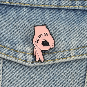 Nahaufnahme der rosa GOTCHA Hand-Emaille-Anstecknadel an einer blauen Jeansjacke