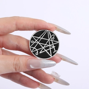 Spilla geometrica in smalto con linee metalliche argentate su sfondo nero in mano
