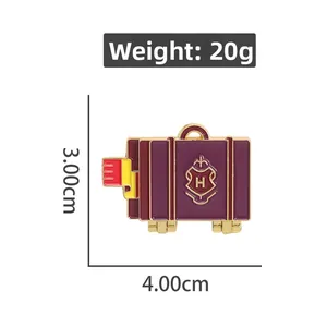Macro detail of alloy suitcase enamel pin with H crest design and gold accents